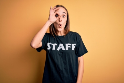 young-beautiful-worker-woman-wearing-staff-uniform-tshirt-isolated-yellow-background-doing-ok-gesture-shocked-with-surprised-face-eye-looking-through-fingers-unbelieving-expression